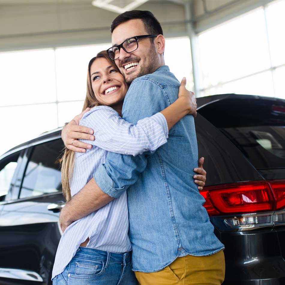 Young couple hugging after buying new car.