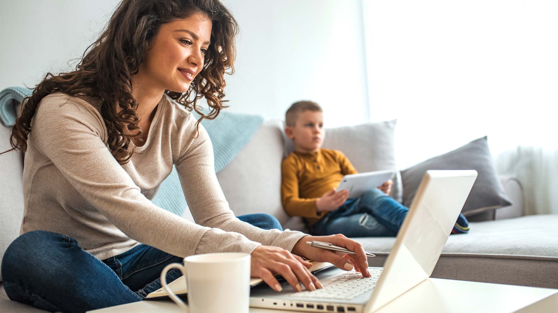 Mother and young son both on electronic devices.